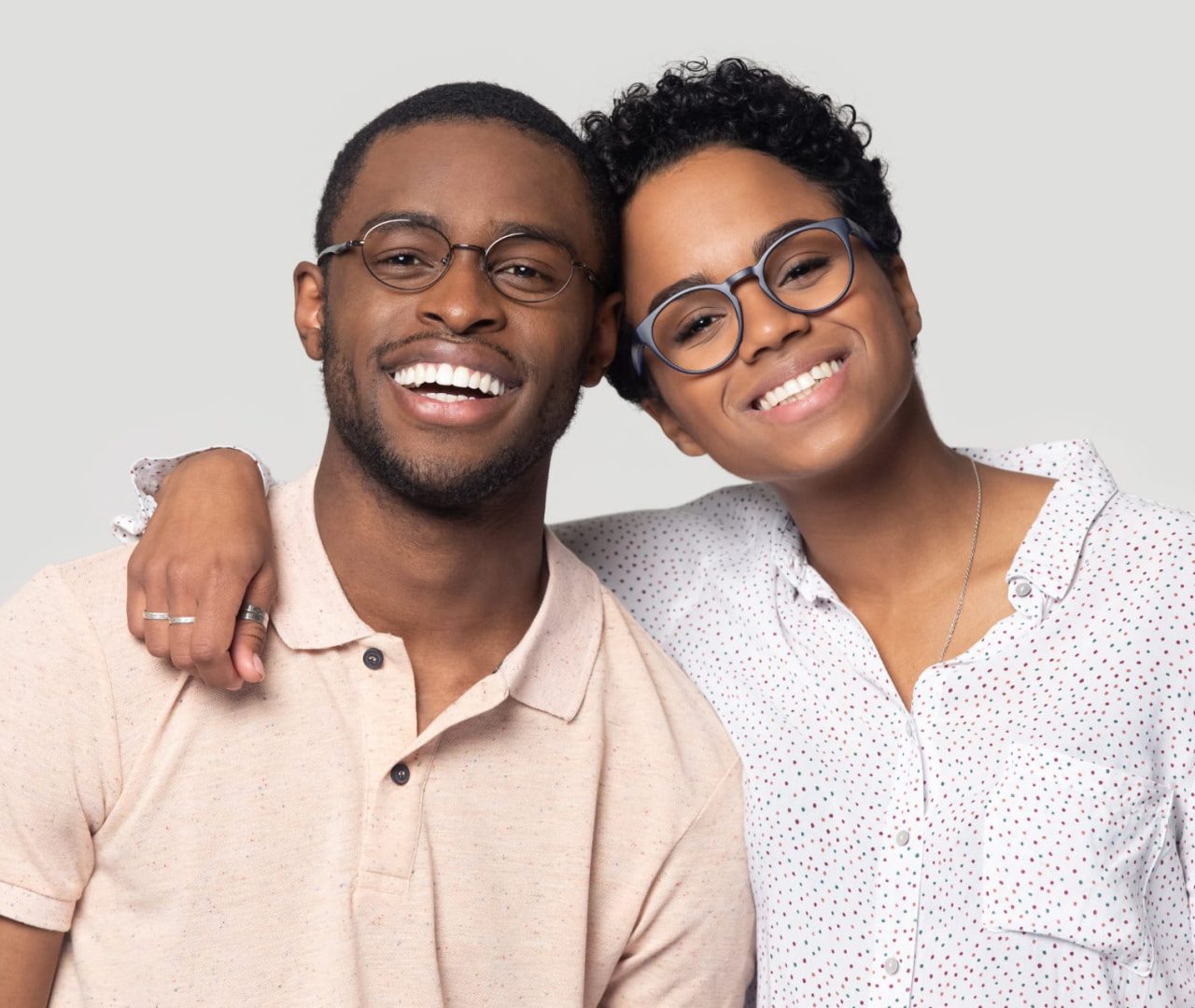 Head shot portrait African attractive married couple in glasses embracing smiling looking at camera posing isolated on grey background, love and relations, clients of photo shooting in studio concept