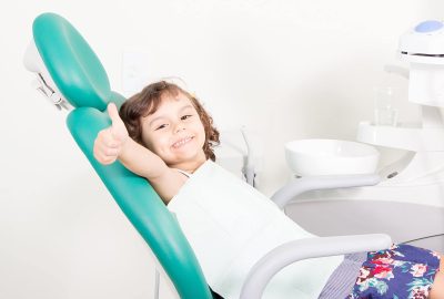 Cute little girl smiling showing Ok sign ( thumb up ) at dental clinic